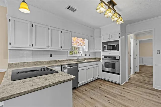 a kitchen with stainless steel appliances granite countertop a stove a sink and a microwave