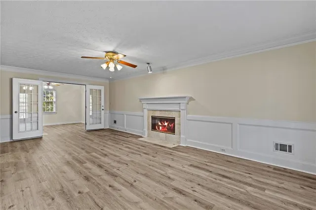 a view of an empty room with wooden floor fireplace and a window