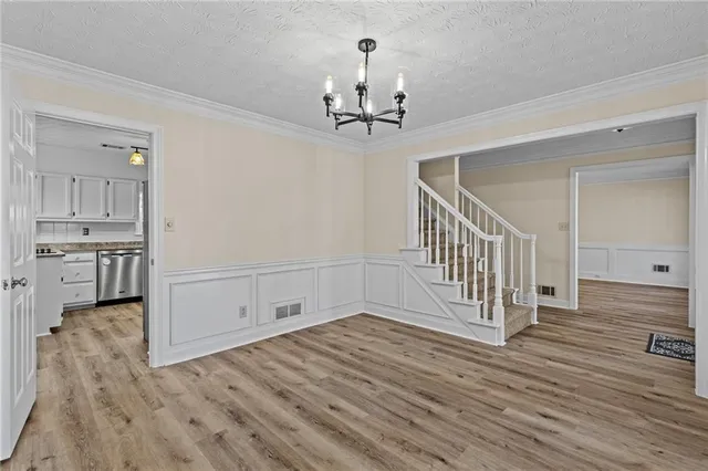 a view of a hallway with wooden floor and a kitchen