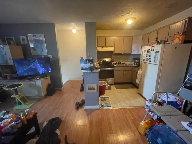 a bedroom with a bed and dresser with wooden floor