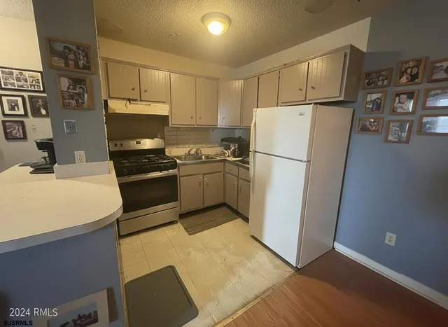 a kitchen with stainless steel appliances a refrigerator sink and white cabinets