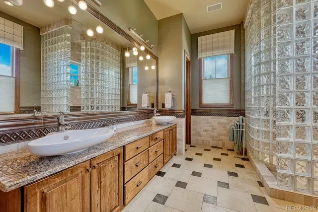a bathroom with a granite countertop sink a mirror and a shower