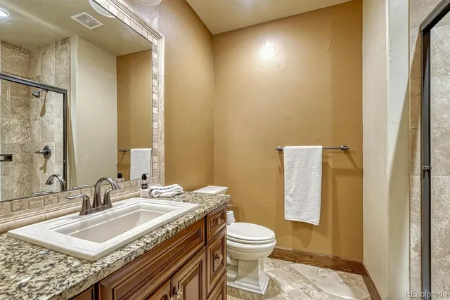 a bathroom with a granite countertop sink a toilet and a mirror