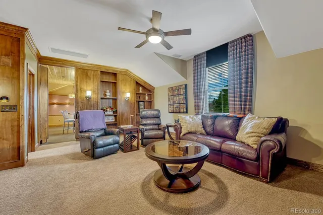 a living room with furniture a ceiling fan and a large window