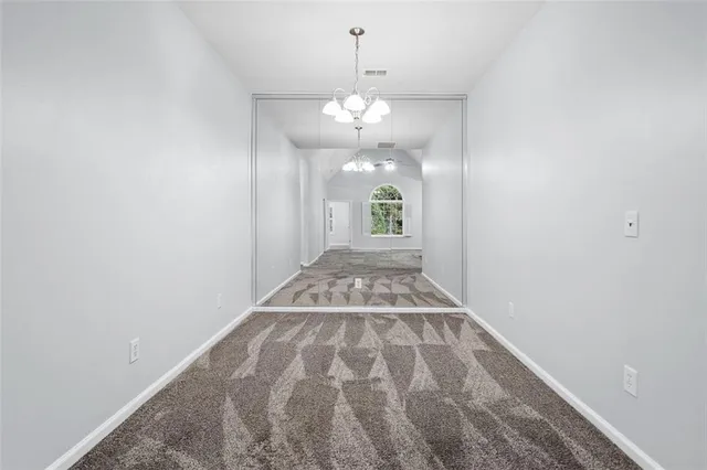 a view of an empty room with window and chandelier fan