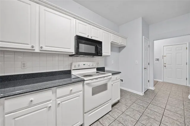 a kitchen with white cabinets and appliances