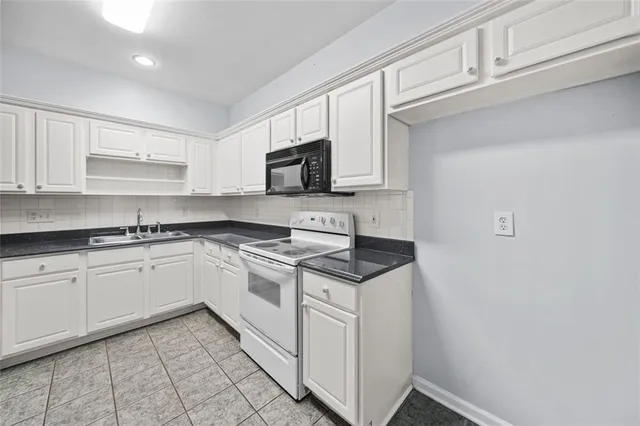 a kitchen with granite countertop white cabinets and white appliances