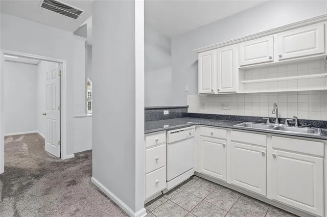 a kitchen with granite countertop white cabinets and sink