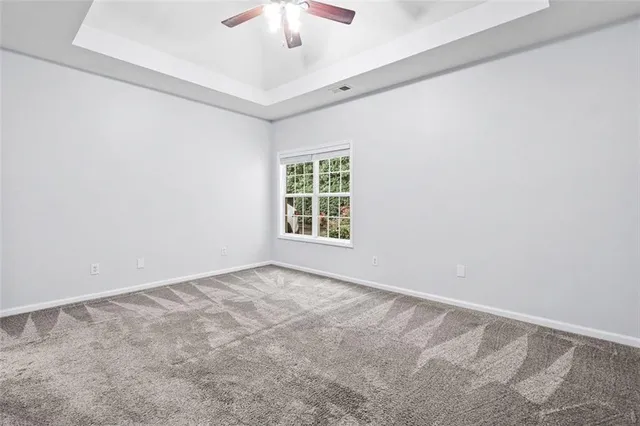an empty room with a chandelier fan and windows