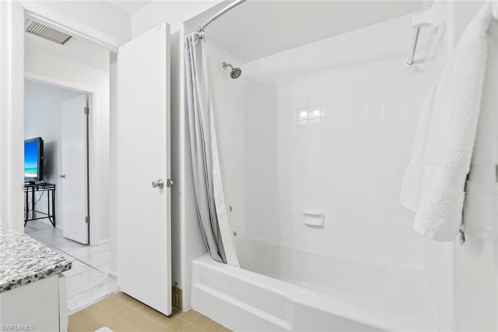 136 Harrison Road, Unit 1 Naples, FL 34112 - Photo 15 of 29 White subway tile shower surround with integrated tub, shower head, and curved shower rod