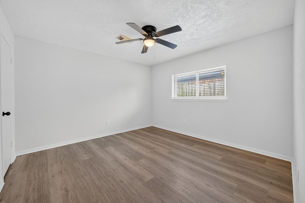 511 Bellmar Lane Friendswood, TX 77546 - Photo 17 of 29 an empty room with wooden floor ceiling fan and windows