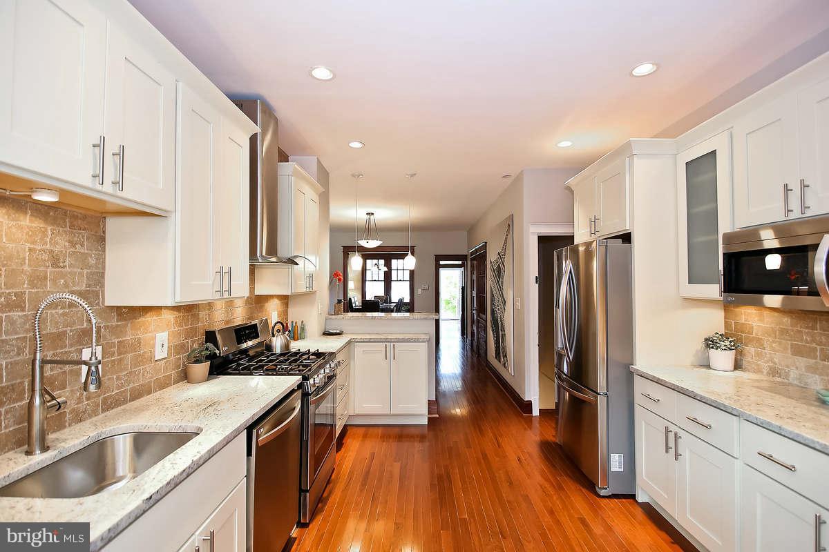 a kitchen with stainless steel appliances a refrigerator a sink a stove a microwave and wooden floor
