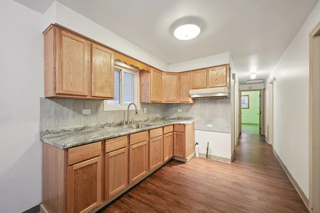 a kitchen with stainless steel appliances granite countertop a sink and cabinets with wooden floor