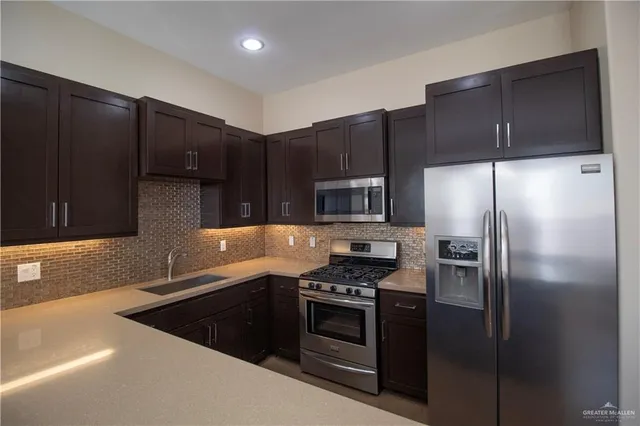 a kitchen that has a sink cabinets and stainless steel appliances