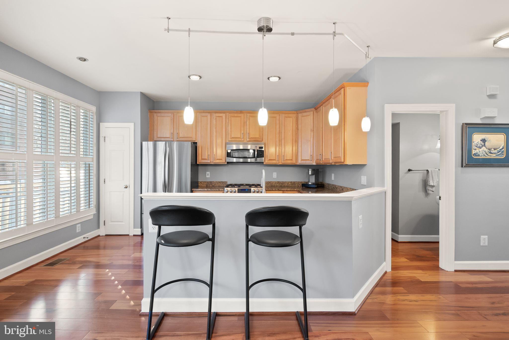 11477 Waterhaven Court Reston, VA 20190 - Photo 19 of 54 a kitchen with stainless steel appliances granite countertop a table chairs in it and wooden floors