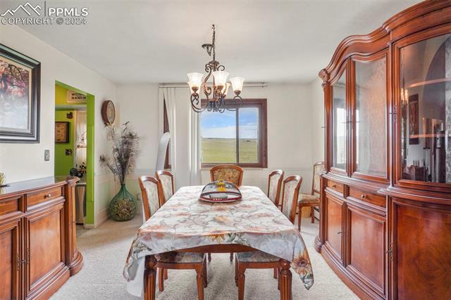 8155 Soap Weed Road Calhan, CO 80808 - Photo 12 of 39 Dining room with a notable chandelier and light colored carpet