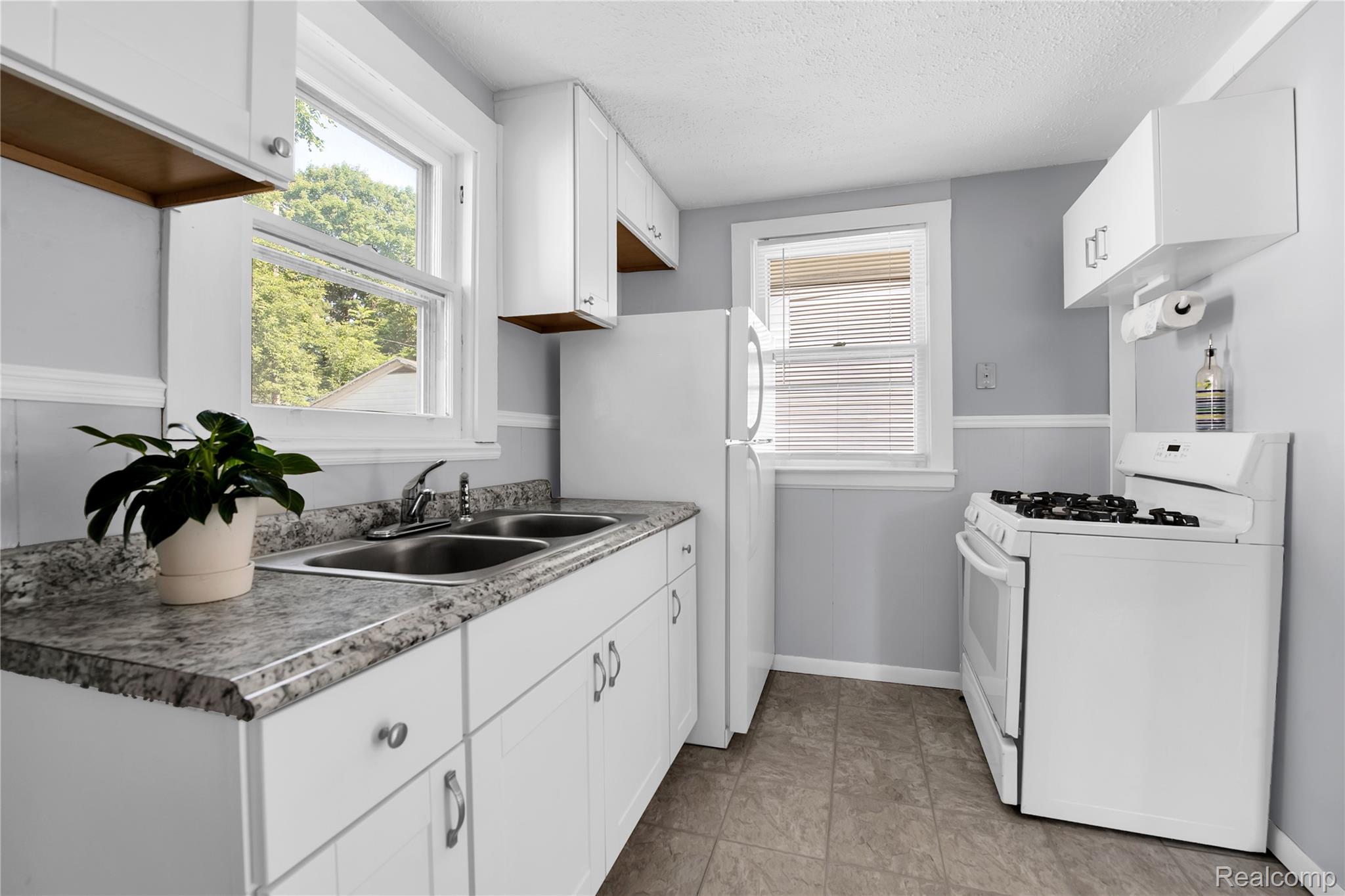 58925 Haven Ridge Road New Haven, MI 48048 - Photo 15 of 22 Kitchen with white appliances, white cabinetry, and a textured ceiling