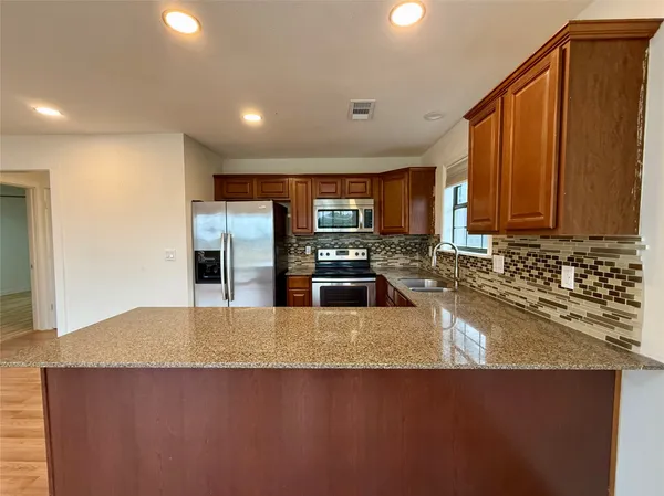a kitchen with stainless steel appliances granite countertop a sink a stove and a refrigerator