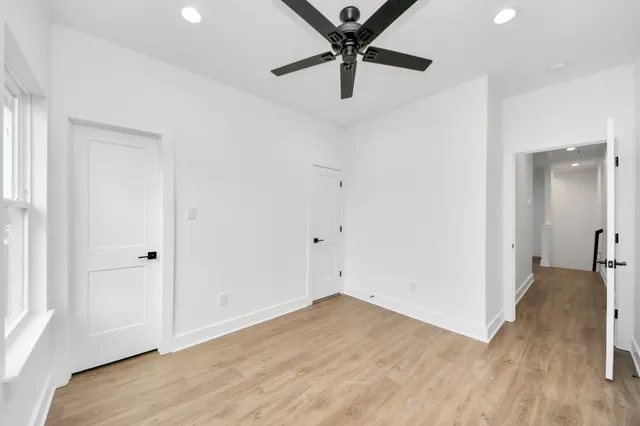 an empty room with wooden floor and a ceiling fan