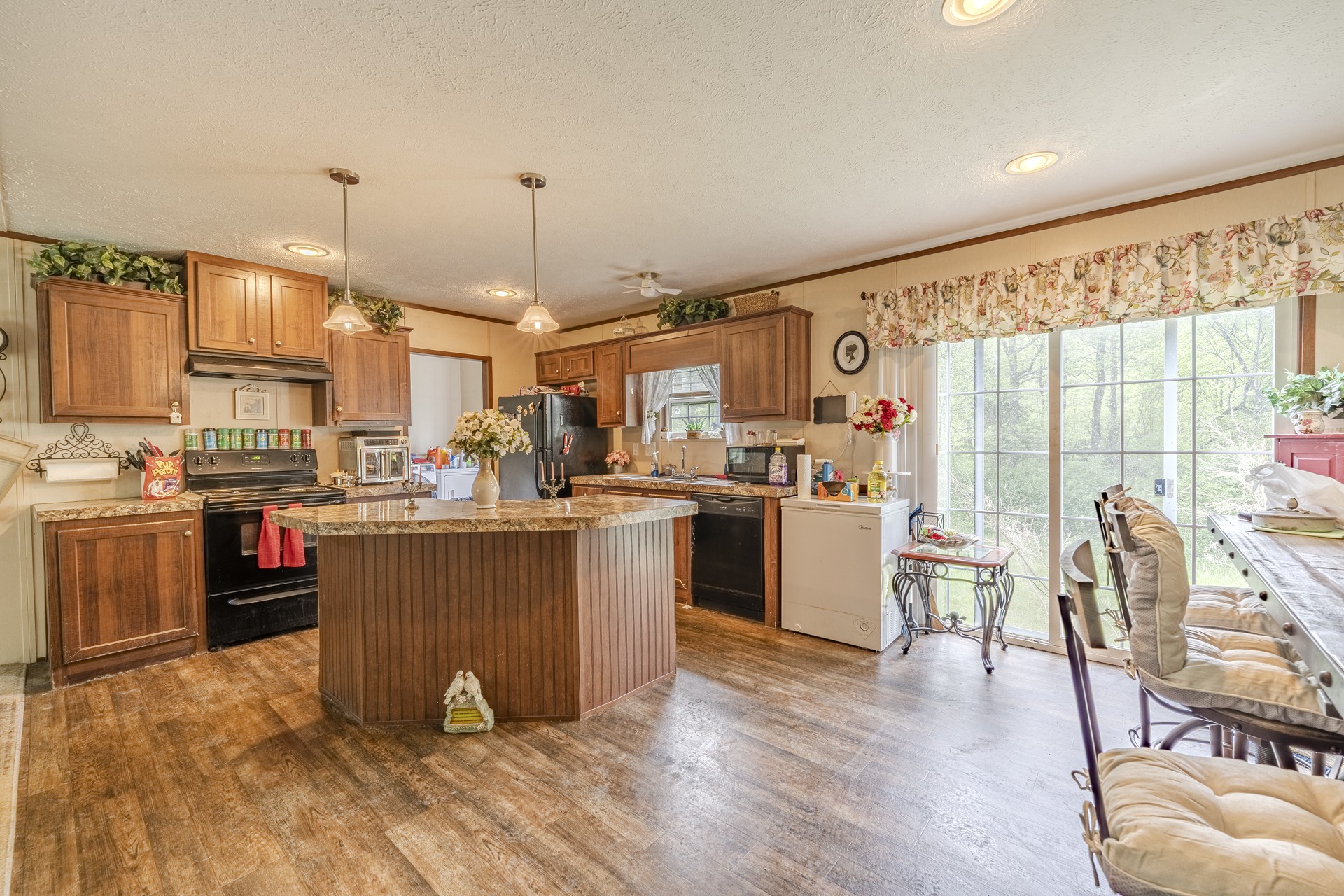 4242 Upper Factory Creek Road Waynesboro, TN 38485 - Photo 9 of 30 a kitchen with stainless steel appliances kitchen island granite countertop a stove top oven a sink dishwasher a dining table and chairs with wooden floor