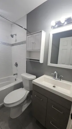 a bathroom with a toilet a sink a tub and mirror