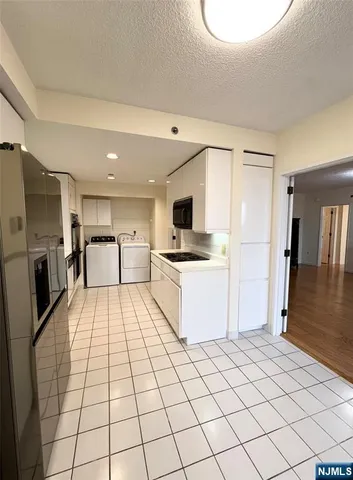 a kitchen with a refrigerator and white cabinets