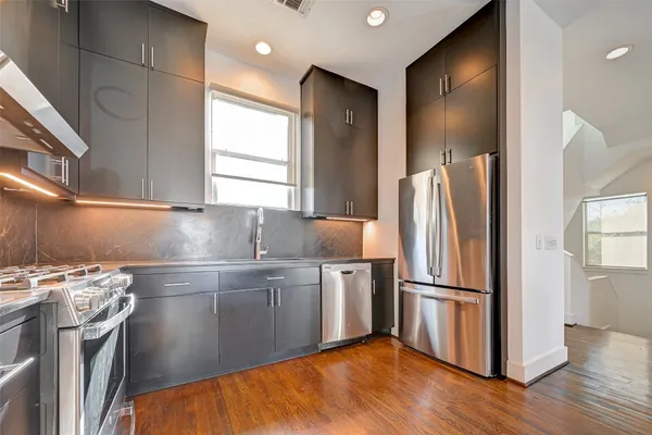 a kitchen with stainless steel appliances a refrigerator and wooden floor