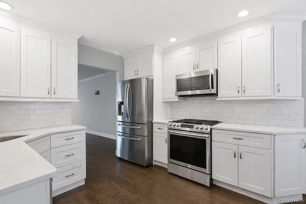 a kitchen with white cabinets and stainless steel appliances
