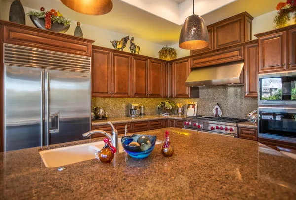 a kitchen with stainless steel appliances granite countertop a sink a stove and a refrigerator