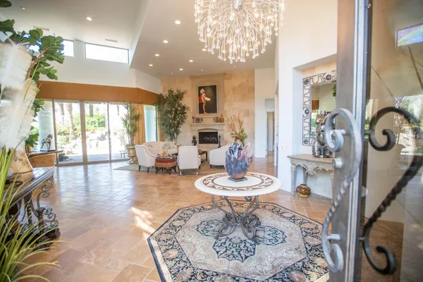 a dining room with wooden floor a chandelier a glass table and chairs