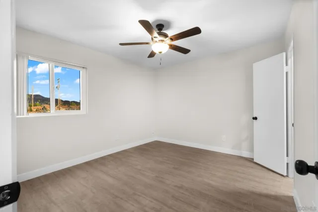 an empty room with ceiling fan and window