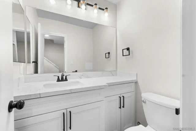 a bathroom with a granite countertop sink a toilet and a mirror
