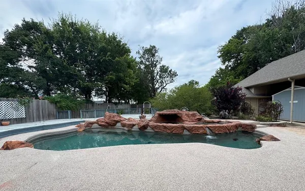 a view of swimming pool with lawn chairs and plants