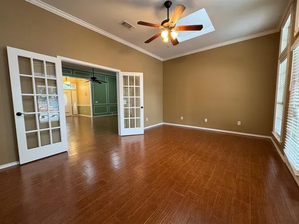 an empty room with wooden floor and windows