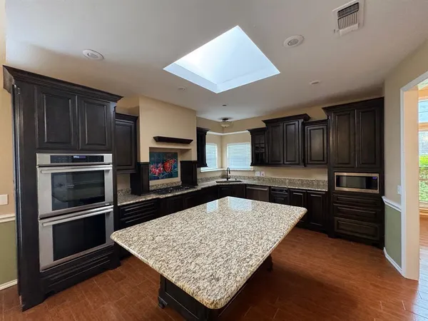a kitchen with stainless steel appliances kitchen island granite countertop a stove and a sink