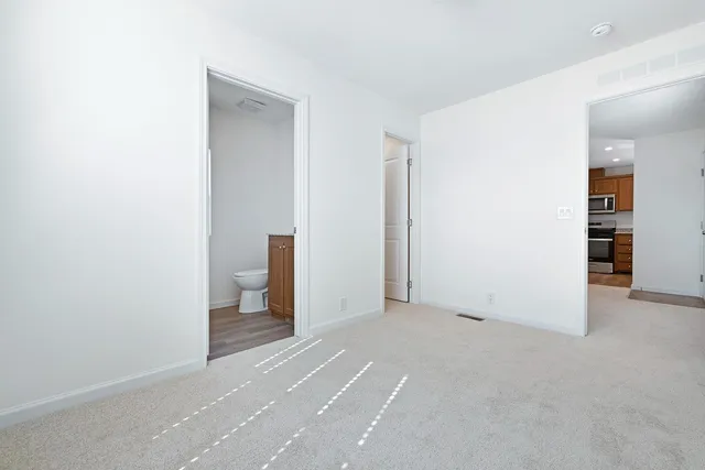 an empty room with an entryway and kitchen