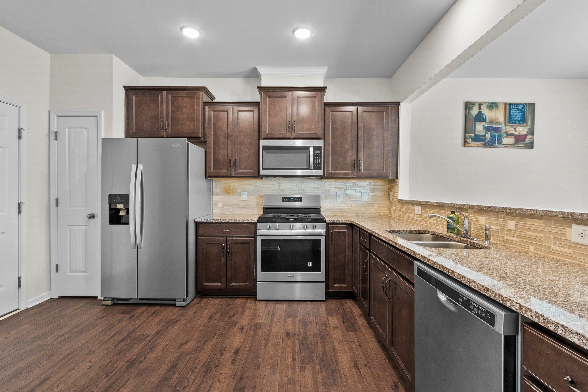 1022 Saffron Loop Durham, NC 27713 - Photo 10 of 22 a kitchen with granite countertop wooden floors stainless steel appliances and a sink