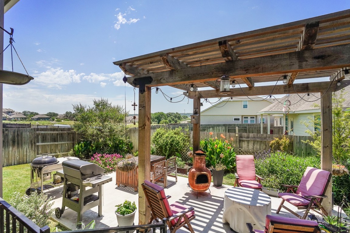 217 Palio Place Georgetown, TX 78628 - Photo 32 of 40 a view of a patio with couches table and chairs under an umbrella with a small yard