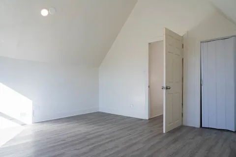 a view of an empty room with wooden floor and closet