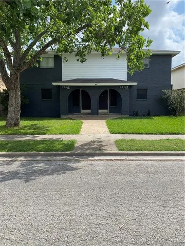 a front view of a house with a garden and trees