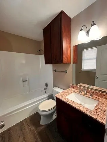 a bathroom with a granite countertop bathtub sink vanity mirror and toilet