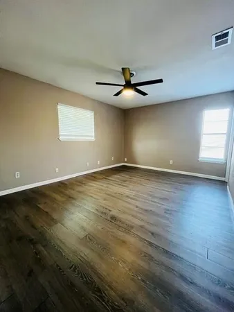 an empty room with wooden floor door and windows