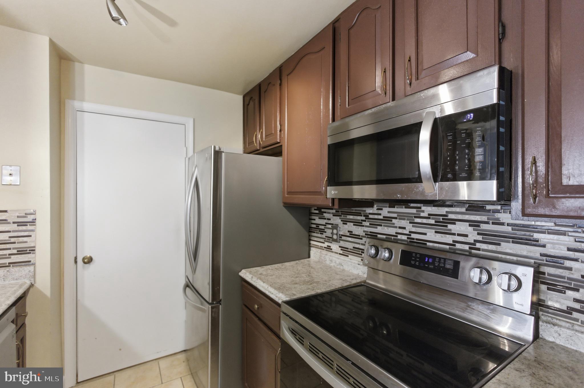 13609 Sir Thomas Way, Unit 1C24 Silver Spring, MD 20904 - Photo 12 of 16 a kitchen with stainless steel appliances granite countertop a stove microwave and refrigerator