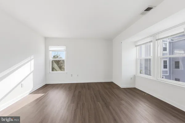 an empty room with wooden floor and windows