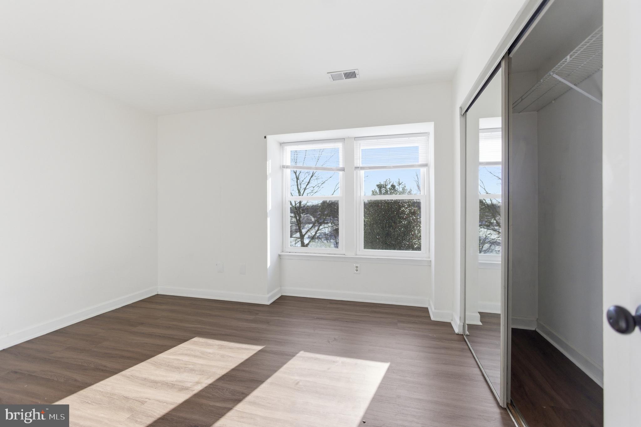 13609 Sir Thomas Way, Unit 1C24 Silver Spring, MD 20904 - Photo 9 of 16 an empty room with wooden floor and windows