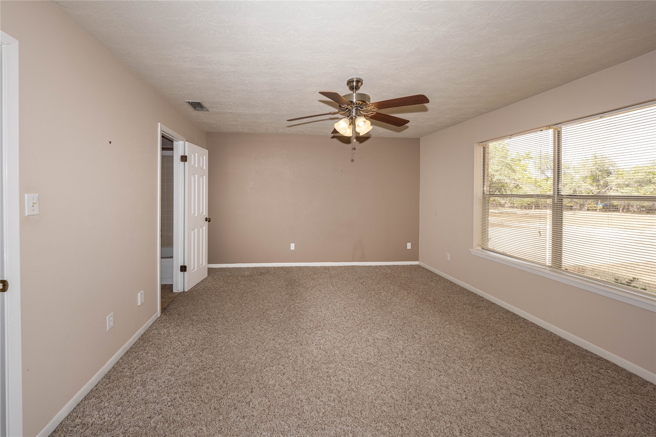 2501 Fischer Store Road Wimberley, TX 78676 - Photo 7 of 23 Primary bedroom featuring neutral-toned walls, plush carpeting, and a ceiling fan with integrated lighting