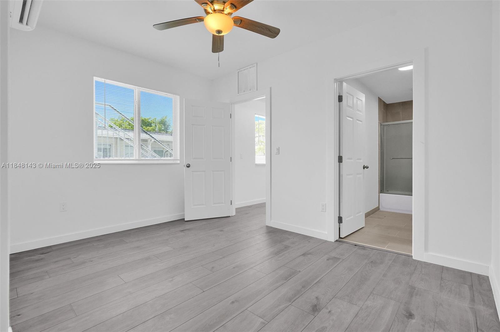 600 Northwest 25th Court Miami, FL 33125 - Photo 4 of 16 an empty room with wooden floor chandelier fan and windows
