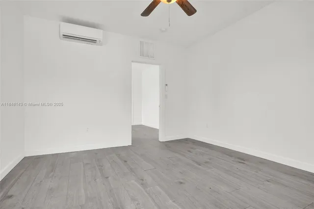 an empty room with wooden floor cabinets and fan