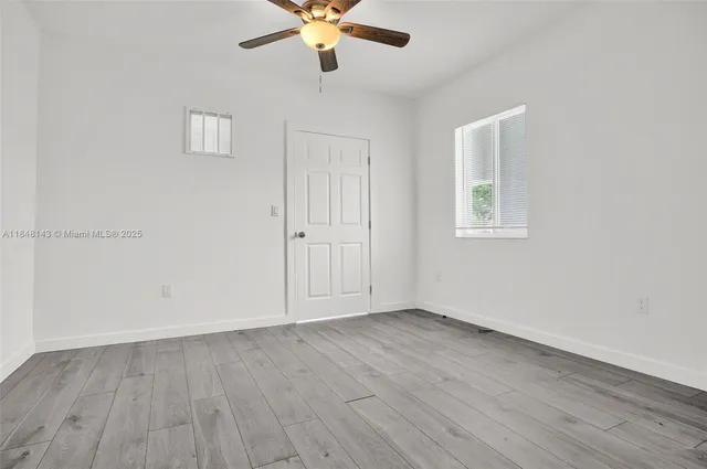 an empty room with wooden floor fan and windows