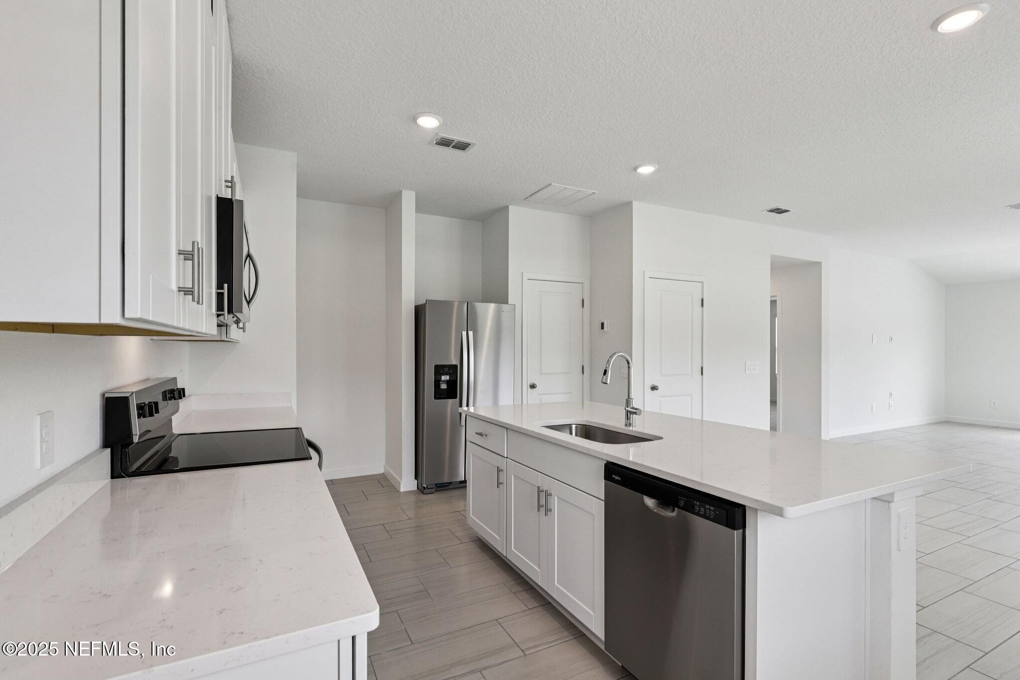 9709 Amber Vlg Road Jacksonville, FL 32219 - Photo 2 of 25 a kitchen with stainless steel appliances a white refrigerator a sink a stove and a refrigerator